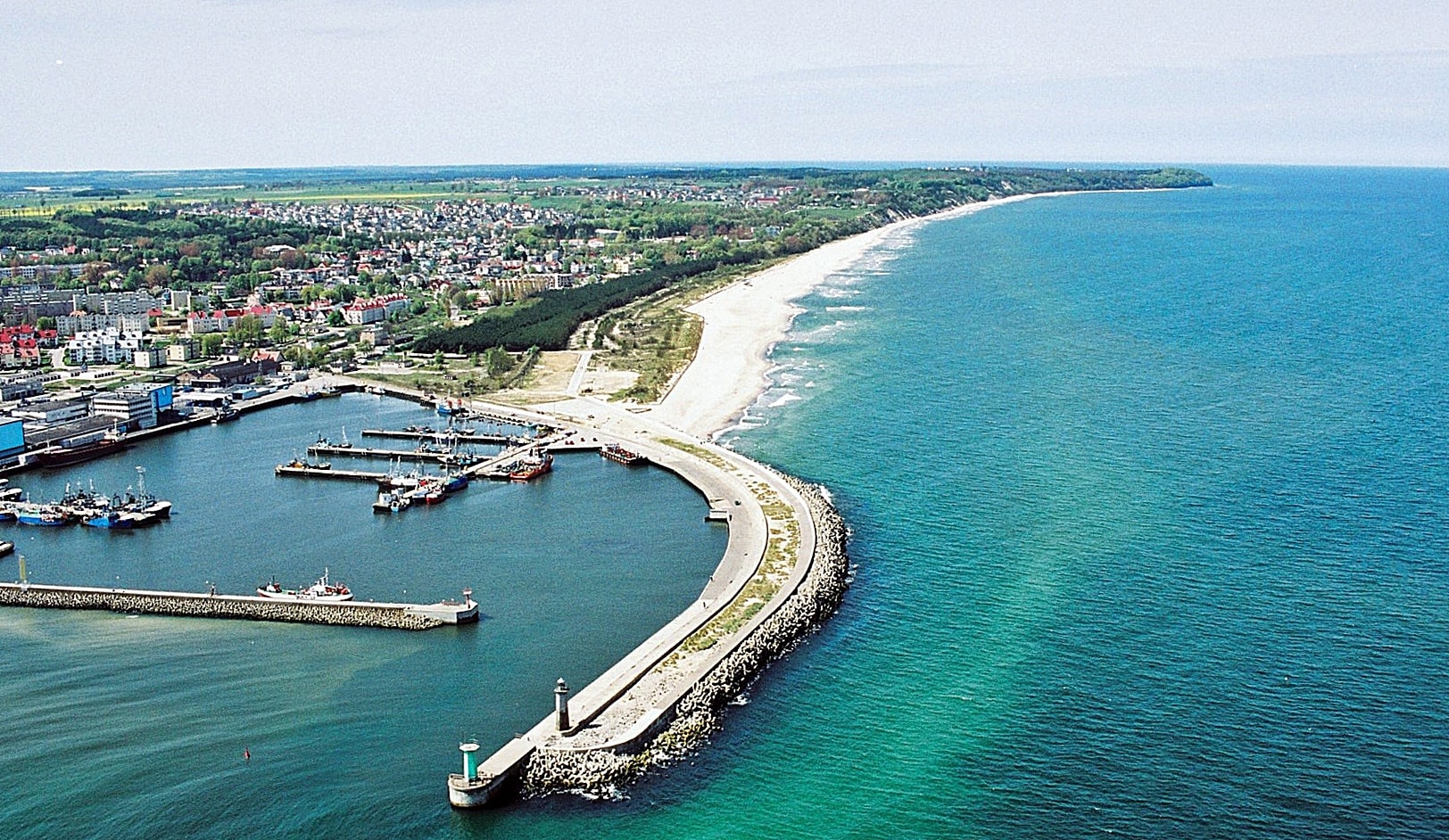 Zdjęcie z lotu ptaka, ukazujące falochron osłonowy portu we Władysławowie na tle panoramy wybrzeża w kierunku północno-zachodnim.