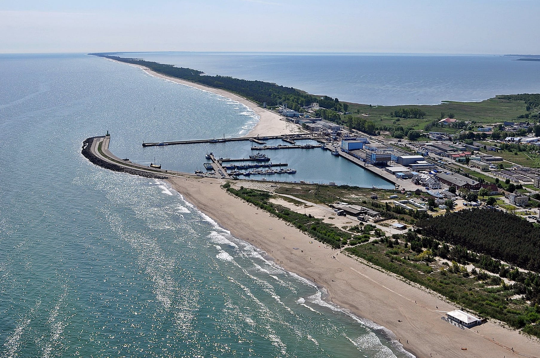 Zdjęcie z lotu ptaka portu we Władysławowie. Widoczne dysproporcje w szerokości plaż przed i za portem.