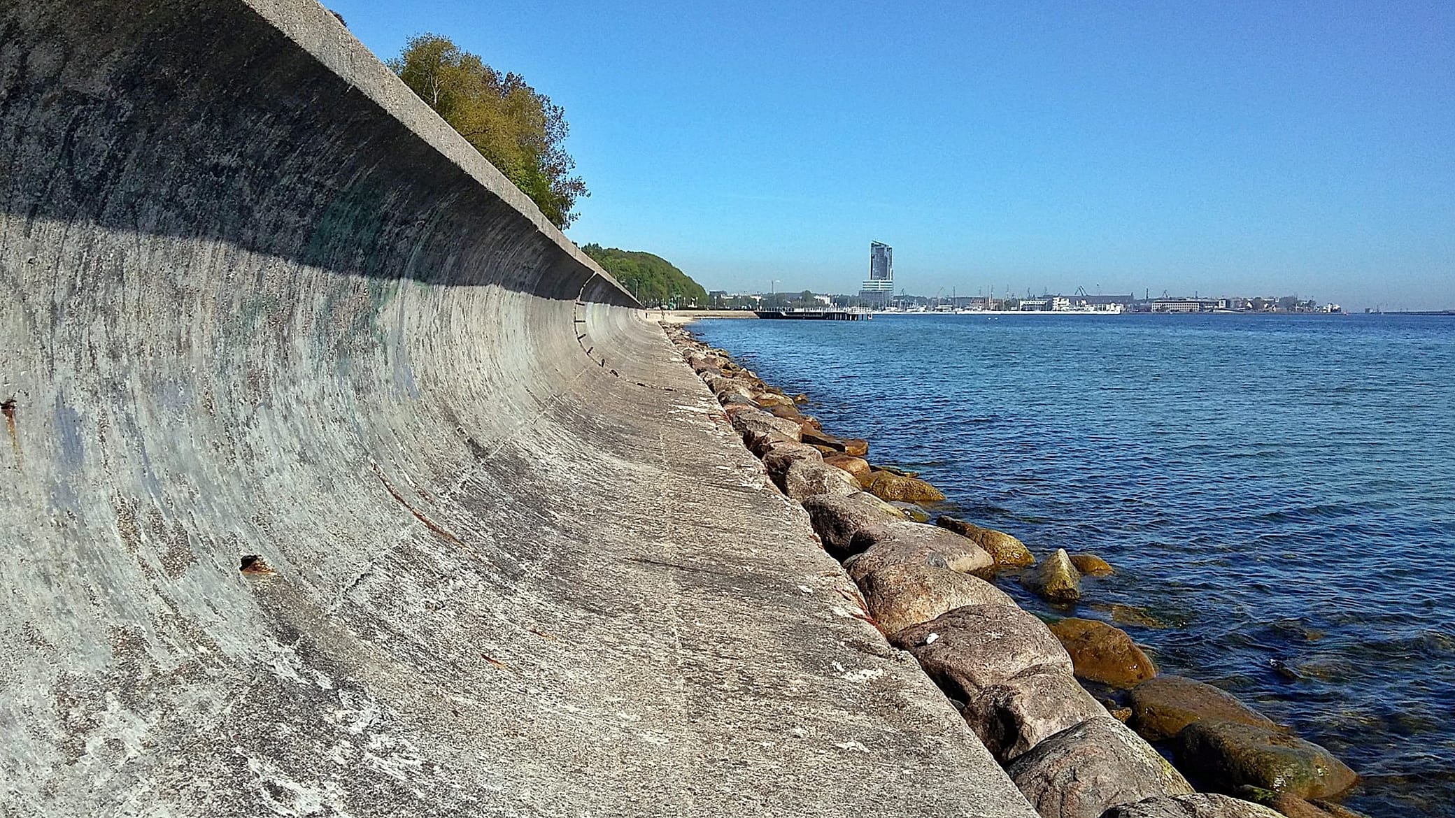 Zdjęcie umocnienia brzegowego w postaci betonowej opaski brzegowej z odbijaczem fal posadowionej na palach, zrobione od strony morza w kierunku północnym.