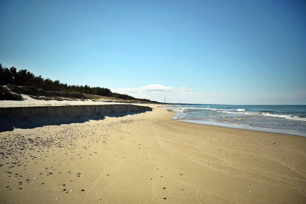 Zdjęcie plaży na Mierzei Wiślanej, z wyraźnie zaznaczonym miejscem, do którego sięgały fale, zabierając piasek.
