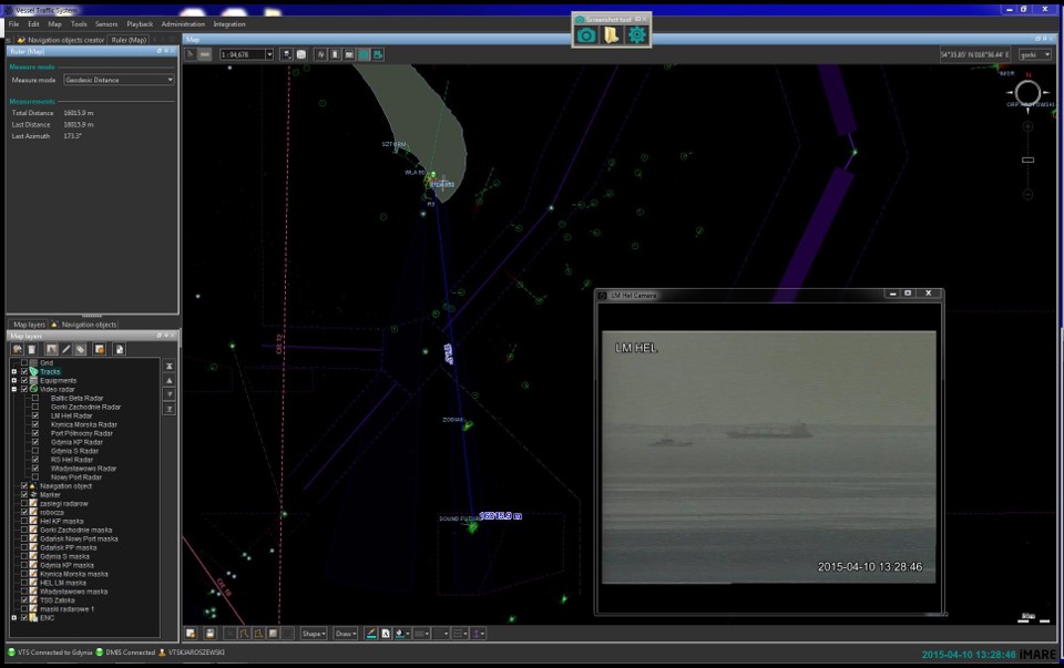 Zrzut ekranu - Wycinek polskiego wybrzeża morskiego – Zatoka Gdańska – widoczny półwysep Hel. Morze w kolorze czarnym, ląd w kolorze szarym. Na purpurowo zaznaczone strefy rozgraniczenia ruchu. Od Helu – w dół granatowa linia, na której w połowie i na końcu (kotwicowisko przy Porcie Północnym w Gdańsku) znajdują się zielone echa statków i ich nazwy. Na morzu – wstawka obrazu z kamery znajdującej się na Helu, przedstawiająca sylwetki dwóch statków, które znajdują się na granatowej linii. 
